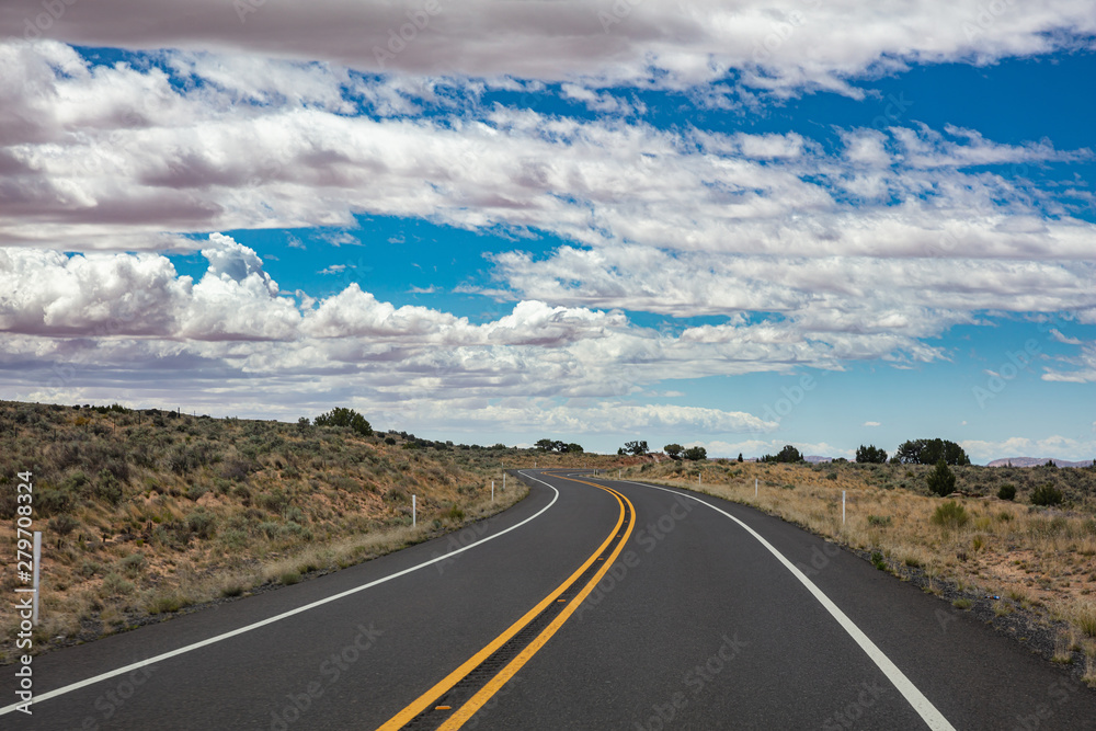 Long winding highway in the american countryside, blue sky with clouds