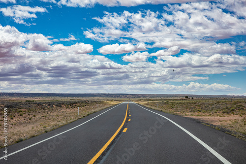 Long highway with ups and downs, cloudy blue sky. USA