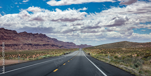 Long highway with ups and downs, cloudy blue sky. USA