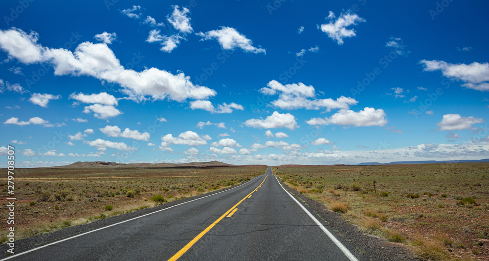 Long highway with ups and downs, cloudy blue sky. USA