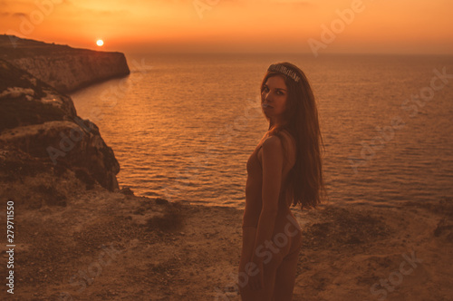 Young woman staying on mountain on shore in body in sunset