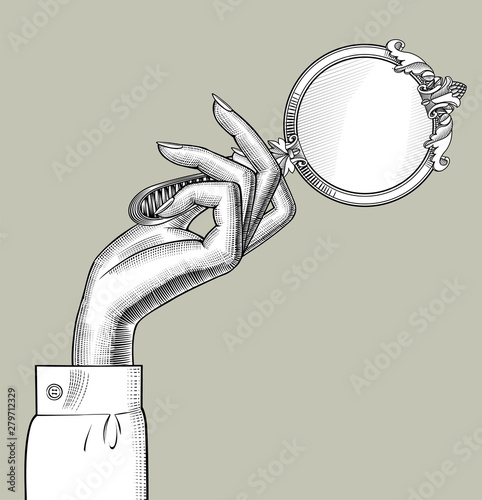 Woman's hand with a round decorative retro mirror