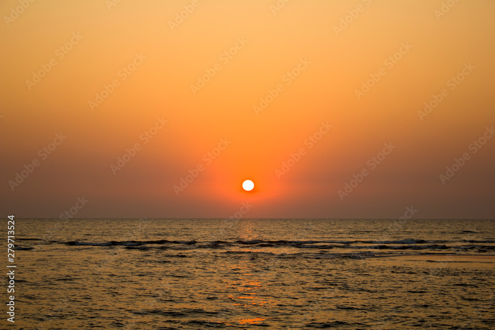 evening ocean with a sun path and waves against the backdrop of a dark yellow, purple, pink sunset sky