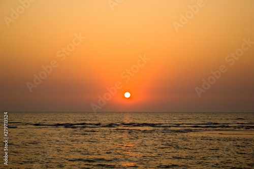 evening ocean with a sun path and waves against the backdrop of a dark yellow  purple  pink sunset sky
