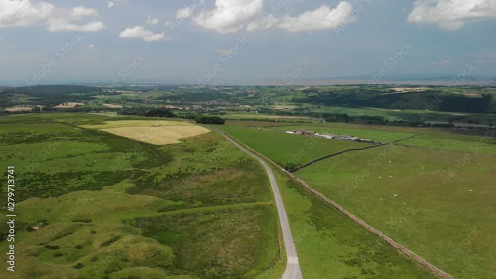 A static aerial shot on Caton Moor, Lancaster. You can see the stunning green countryside on a sunny yet cloudy Summers day. Looking out towards Grange-over-Sands. A static aerial shot on Caton Moor, Lancaster. You can see the stunning green countryside on a sunny yet cloudy Summers day. Looking out towards Grange-over-Sands.