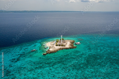 Aerial view of a tiny tropical island with a lighthouse surrounded by a huge coral reef (Capitancillo Island, Philippines)
