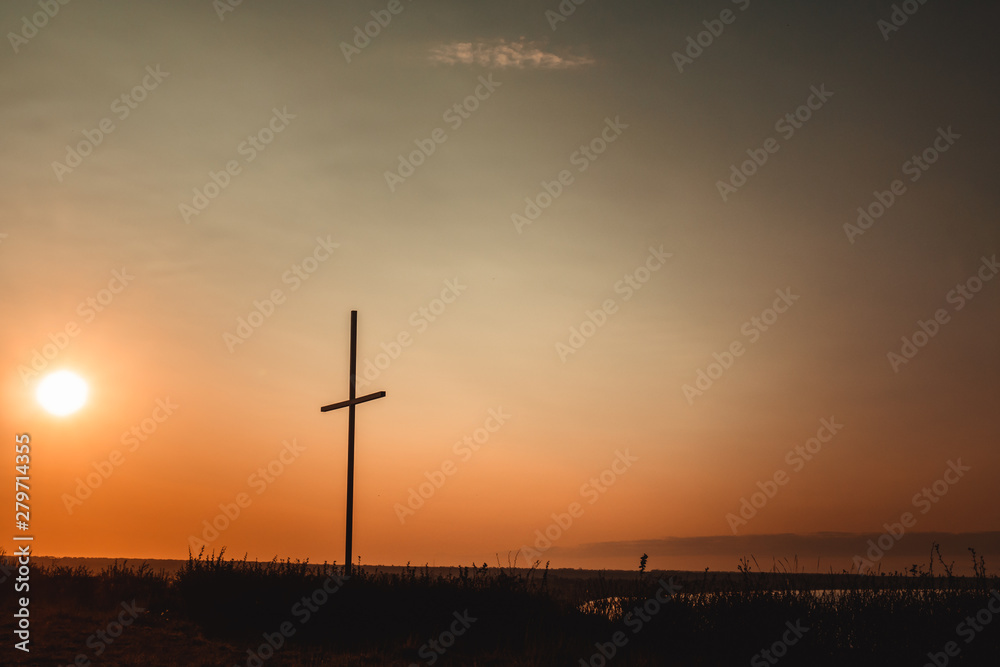 Concept conceptual black cross religion symbol silhouette in grass over sunset or sunrise sky, Resurrection of Jesus, Cross christian