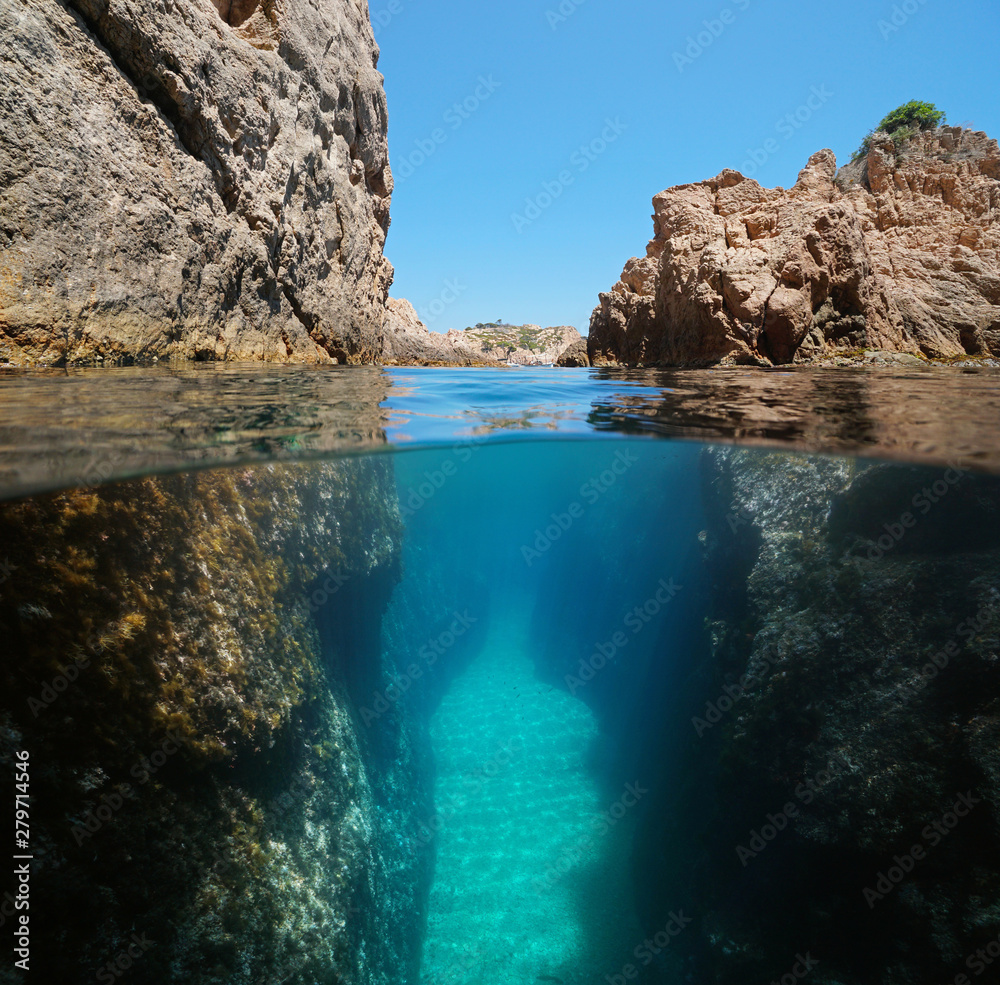 Narrow passage between rocks on the seashore, split view over and under water surface, Mediterranean sea, Spain, Costa Brava, Aigua Xelida, Palafrugell, Catalonia