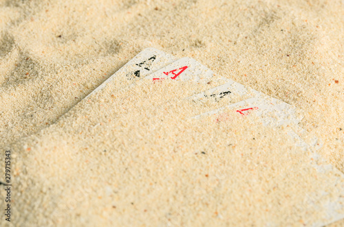 Poker playing cards buried in a sand dune