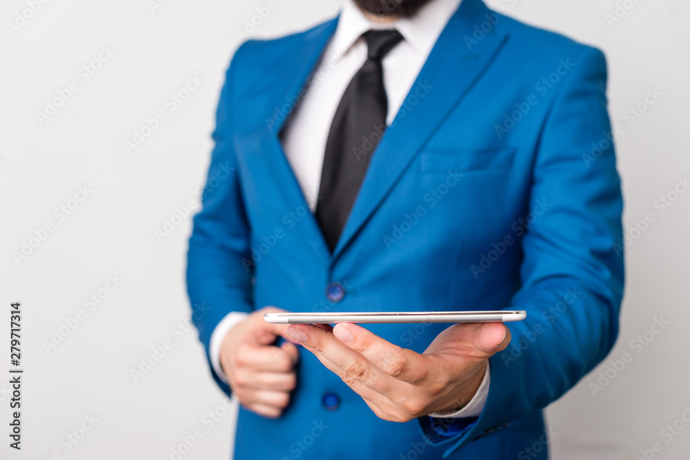 Businessman in blue suite with a tie holds lap top in hands.