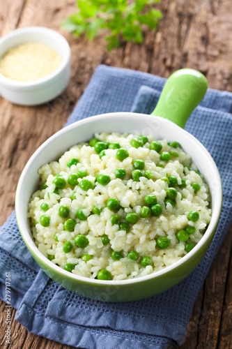 Fresh homemade creamy green pea risotto in green bowl, grated cheese in the back (Selective Focus, Focus one third into the risotto) photo