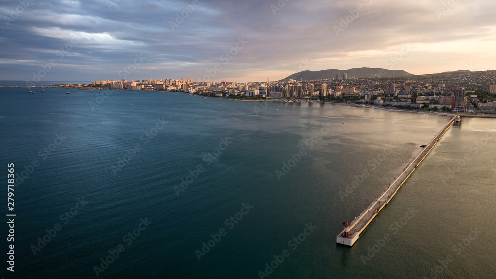 Pier with a lighthouse in the city of Novorossiysk from a height where you can see the sea, the bay at sunset.