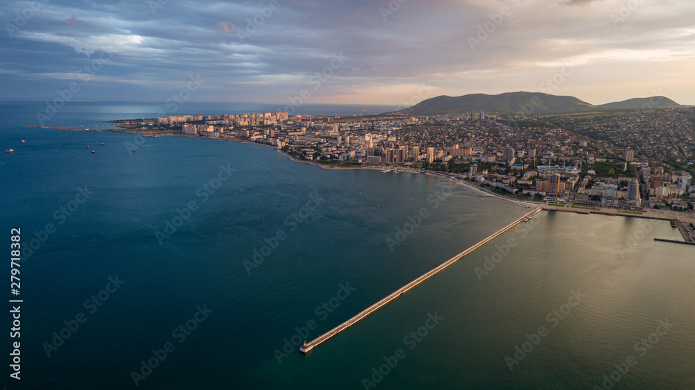 Pier with a lighthouse in the city of Novorossiysk from a height where you can see the sea, the bay at sunset.