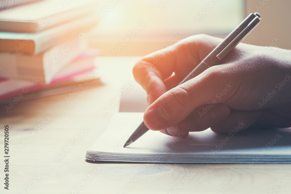 female hands writing notes on notebook with pen