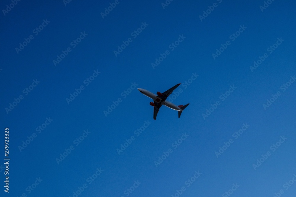 Airplane flying over business skyscrapers, high-rise buildings. Transport, transportation, travel. Sun light on blue sky. Airplane flying over business skyscrapers, high-rise buildings. Transport, transportation, travel. Sun light on blue sky.