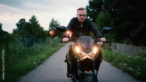 young male biker rides a modern motorcycle along an empty road in the evening. Biker life style.