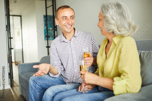 Portrait of happy mature couple drinking champagne while chatting during party, copy space