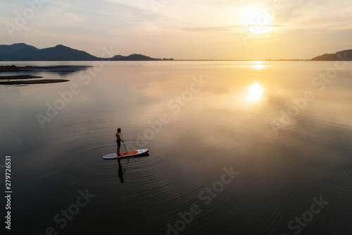 Принти на полотні Silhouette Aerial view of stand up paddle boarder paddling at sunset on a flat warm quiet river