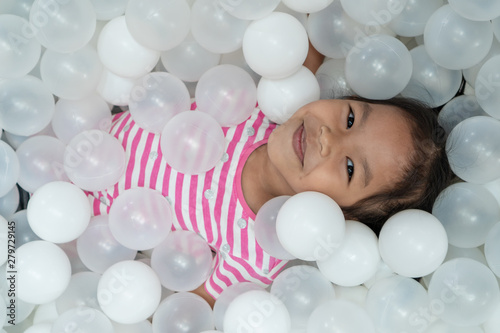 Happy cute asian child girl having fun to play with white plastic balls in the playground photo