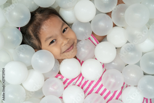 Happy cute asian child girl having fun to play with white plastic balls in the playground photo