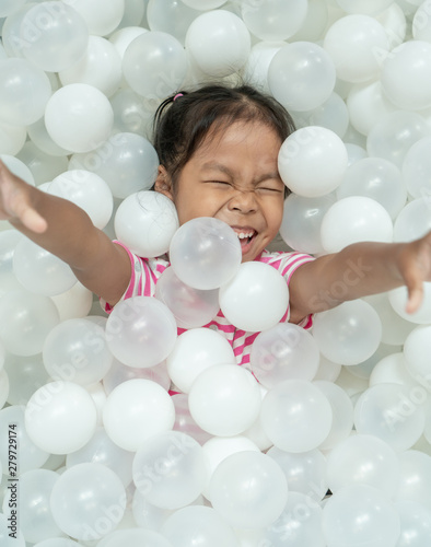 Happy cute asian child girl having fun to play with white plastic balls in the playground photo