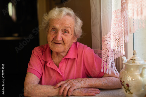 Portrait of old woman sitting at the table.