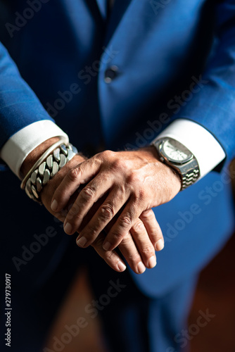 Close up of man in blue suit with chain and watch on his wrists
