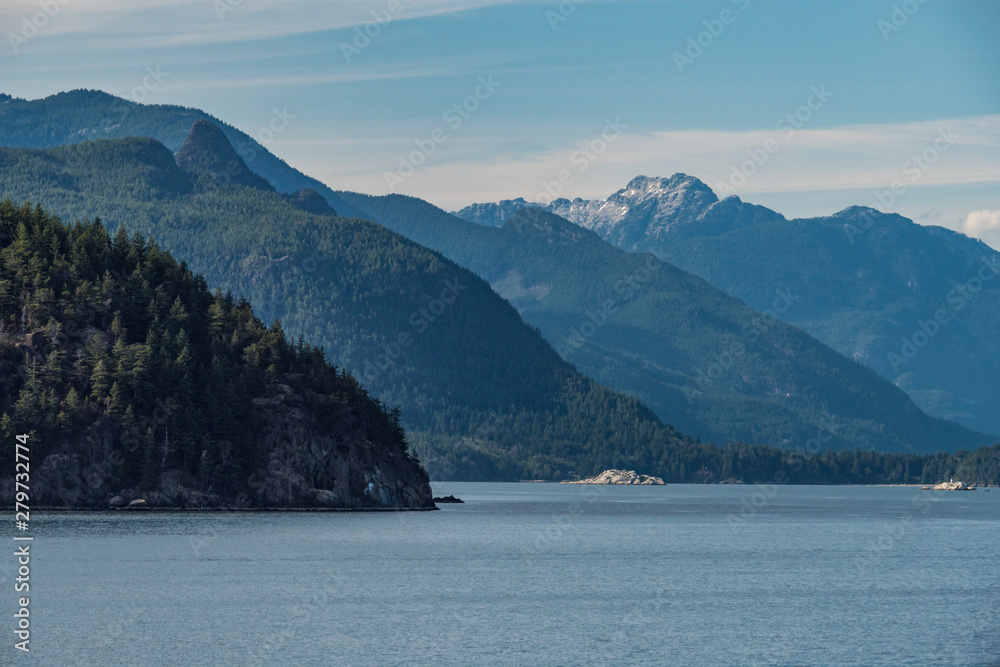 layers of forest covered mountains on the island over the horizon of the ocean under cloudy blue sky layers of forest covered mountains on the island over the horizon of the ocean under cloudy blue sky