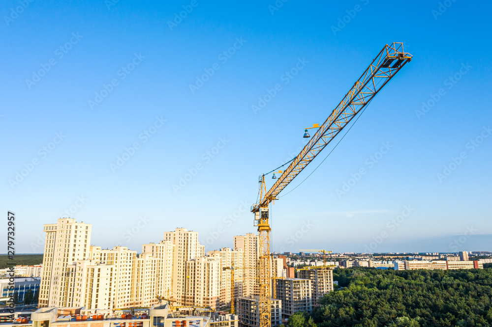 aerial panoramic view of new apartment building under construction and high yellow crane against blue sky background