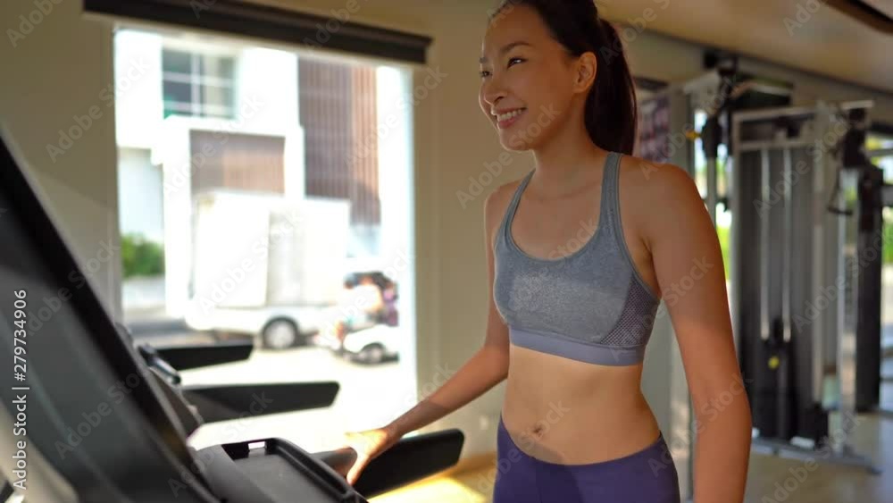 A happy young woman enjoys her morning work out routine on the treadmill A happy young woman enjoys her morning work out routine on the treadmill