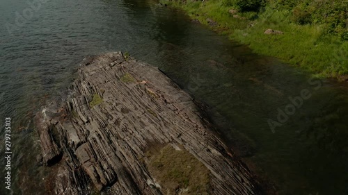 Moving, aerial footage of a rock in the river, shot along highway 16 in between Terrace and Prince Rupert around the Skeena River in north-west B.C. Canada during the summer months. photo