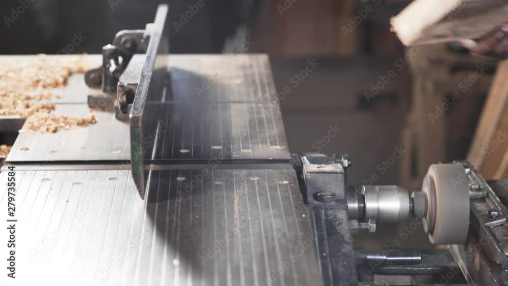 Wooden plank being smoothened with a machine at a saw mill, close up