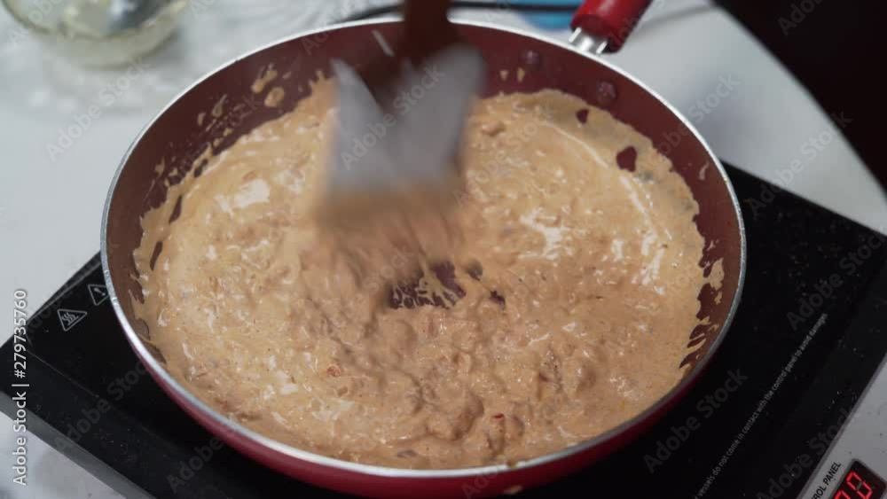 A cook stirring frying creamy sauce into a pan for preparing a ketogenic diet dish A cook stirring frying creamy sauce into a pan for preparing a ketogenic diet dish
