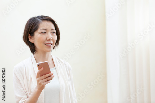 スマートフォンを持っている笑顔の女性 Free Download スマートフォンを持っている笑顔の女性 - GFXLoad