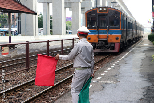 Train officer is acting to signal safety precautions for passengers and people while the train is landing at the platform.
