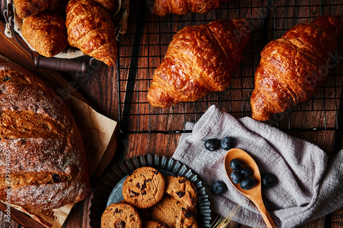 Delicious pastry and wheat spikes on the wooden table