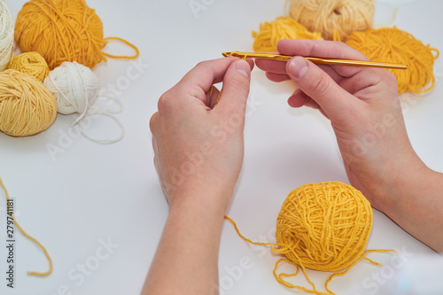 Obraz na płótnie girl knits crochet, on a white background, the process of knitting close-up, yellow ball of thread w salonie