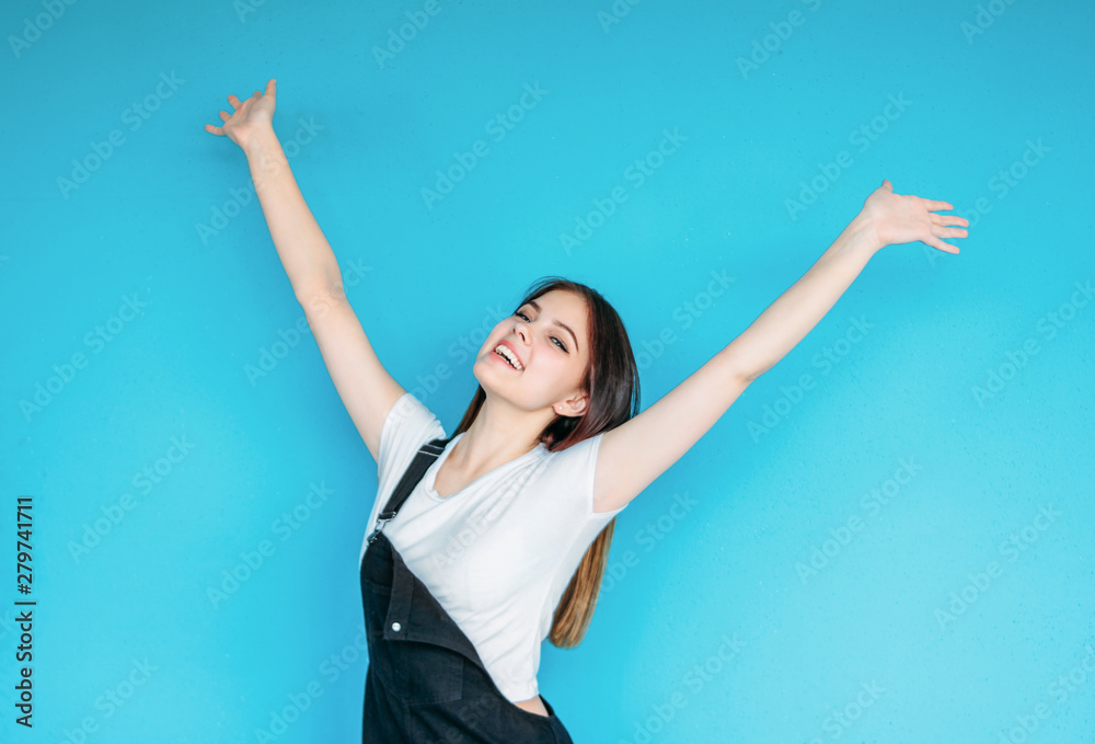 Fototapeta premium Happy carefree girl with dark long hair in white t-shirt isolated on blue background