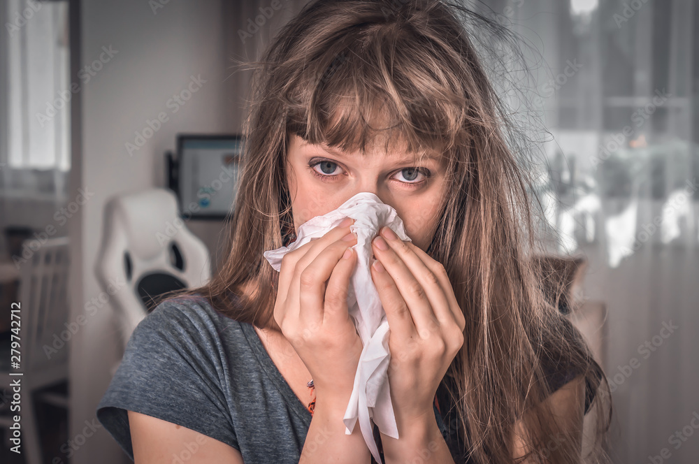 Sick woman with flu or cold sneezing into handkerchief
