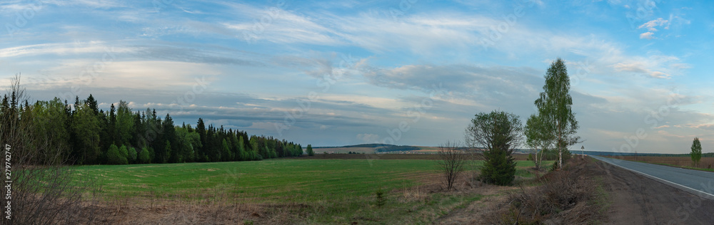 A quiet spring evening in an open area with fields, forests, hills, trees and a road. Zavyalovsky district, Udmurt Republic, Russia