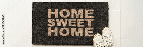 Home condo door mat sweet home doormat text at condo entrance with casual shoes panoramic banner. House move in concept.