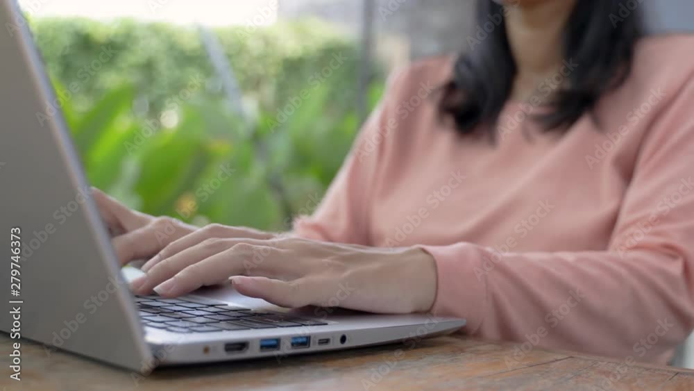 young asian woman typing with a laptop doing work