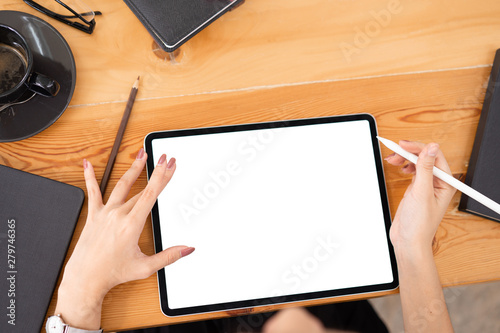 Top view image shot of businesswoman hands using tablet with isolated screen on woden desk at office workplace.