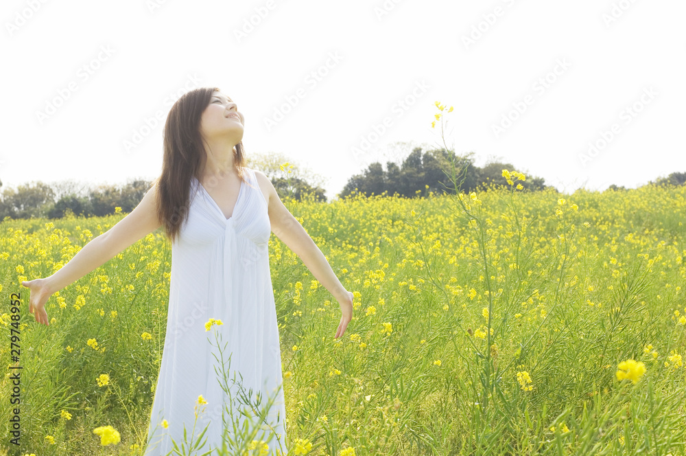 Fototapeta premium 菜の花畑で大きくてを広げる女性