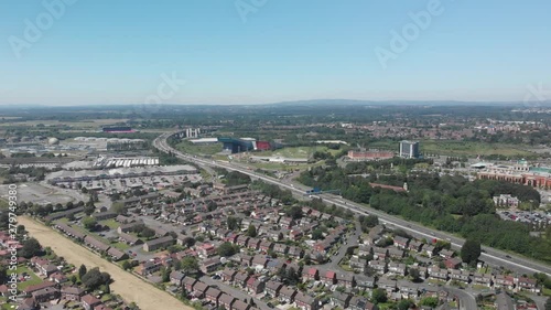 A static shot looking out over the M60 motorway on a Summer day in Manchester, England with Manchester skyline in the background. You can see many of the houses in the area and the M60 motorway.