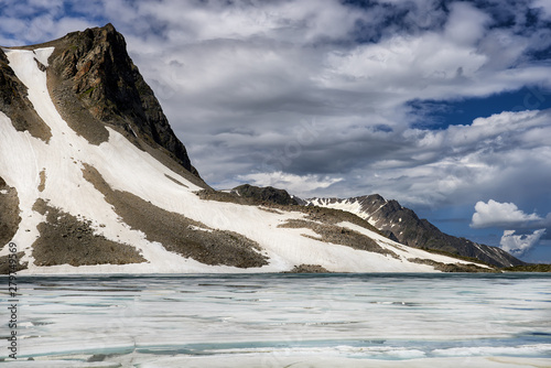 Glacier on mountain and lake with floating ice on surface photo