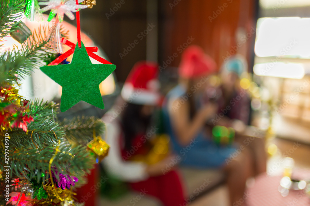 Naklejka premium Christmas tree and green star with blurred background of people in Christmas party, with copy space for text