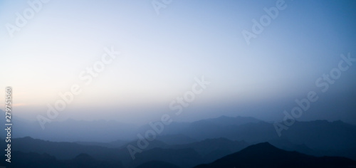 landscape with silhouettes of blue mountains with mist and cold sunlight