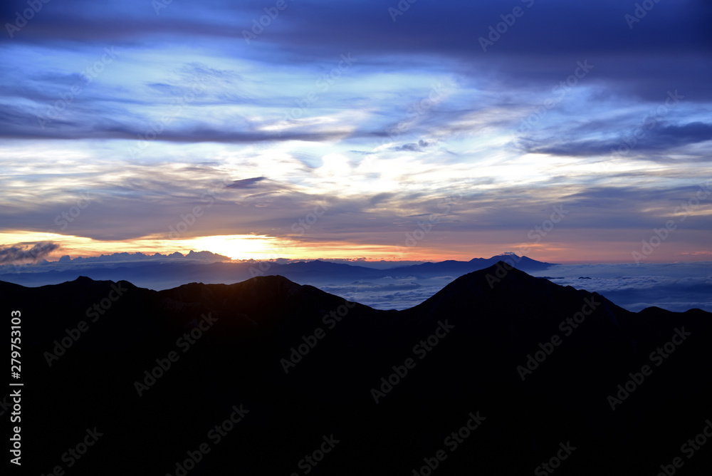 breaking Dawn; silhouette of mountain ridgeline and sea of clouds breaking Dawn; silhouette of mountain ridgeline and sea of clouds
