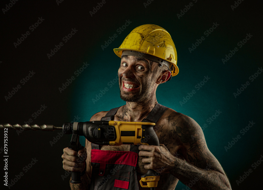 A man miner in a worker s clothes and a helmet, dirty, in soot, with a naked body, grimaces at the camera A man miner in a worker s clothes and a helmet, dirty, in soot, with a naked body, grimaces at the camera